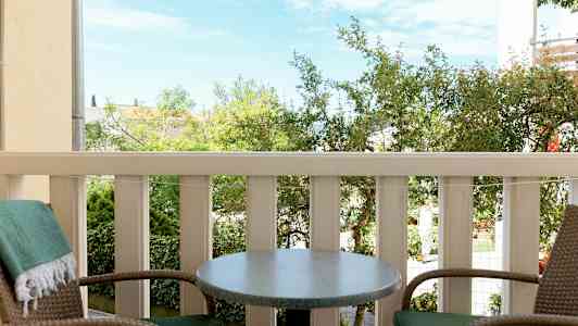 To stoler og et bord på en balkong med utsikt over grøntområde (AI-generert tekst)