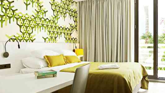 Moderne hotellrom med grønn dekorert vegg og store vinduer. (AI-generert tekst)