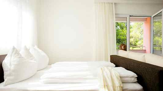 Et lyst rom med en seng nær vindu og balkong. (AI-generert tekst)