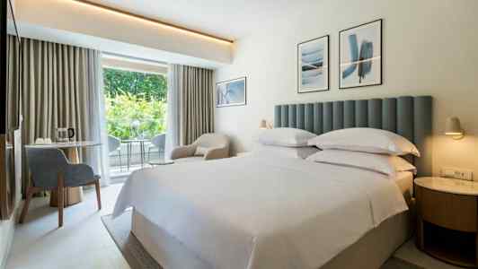 Hotellrom med dobbeltseng og lys innredning. (AI-generert tekst)