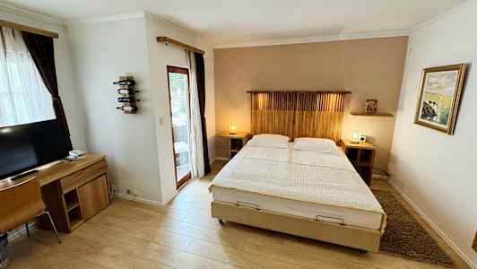 Bilde av et hotellrom med dobbeltseng, skrivebord og TV. (AI-generert tekst)