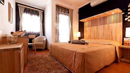 Et hotellrom med treinnredning, en dobbeltseng og store vinduer. (AI-generert tekst)