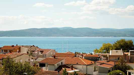 Røde hustak med sjøen og åser i bakgrunnen. (AI-generert tekst)