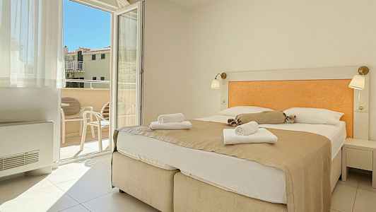 Rom med dobbeltseng og utsikt mot balkong. (AI-generert tekst)