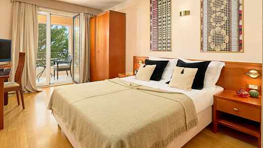 Dobbeltrom med dobbeltseng, utsikt mot balkong med sittemøbler. (AI-generert tekst)