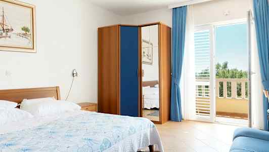 Et hotellrom med en seng, et skap med speildør og en balkong. (AI-generert tekst)