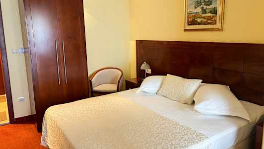 Hotellrom med en dobbeltseng, nattbord og garderobe. (AI-generert tekst)