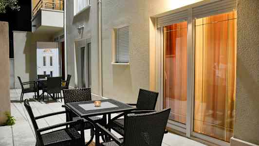 Utemøbler foran en bygning med vinduer og dør. (AI-generert tekst)