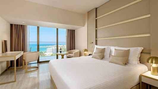 Et moderne hotellrom med en stor seng og utsikt over havet. (AI-generert tekst)