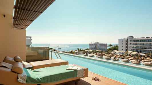 Solstoler og basseng med utsikt over havet på en ferieby. (AI-generert tekst)