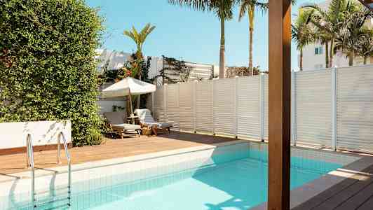 Et svømmebasseng med soldekk og solsenger i tropisk miljø. (AI-generert tekst)