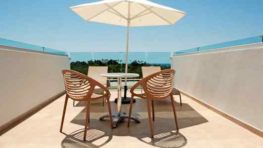 Bilde av en terrasse med to stoler, et bord og en parasoll. (AI-generert tekst)