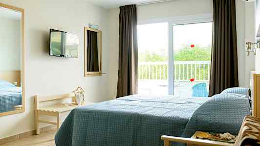 Et hotellrom med en seng ved siden av en glassdør som fører til en balkong. (AI-generert tekst)