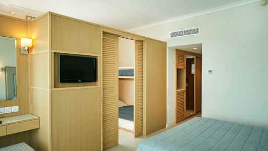 Et hotellrom med en TV, garderober og en dobbeltseng. (AI-generert tekst)