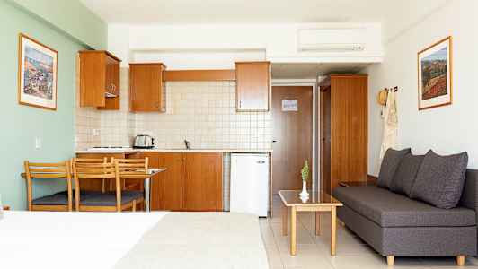 Et hotellstudio med kjøkken, spisebord og sittegruppe. (AI-generert tekst)