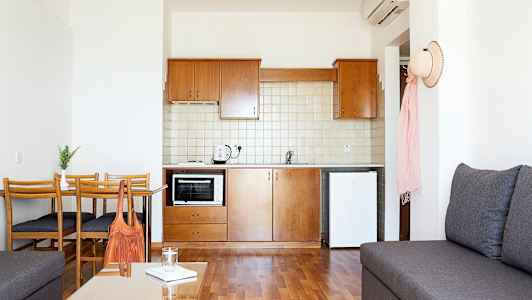 Et lite kjøkken med tremøbler og hvite vegger. (AI-generert tekst)