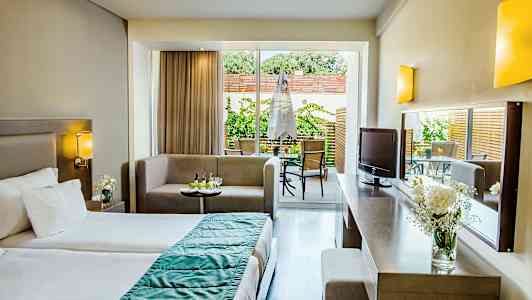 Et hotellrom med en seng, sittegruppe og utgang til en terrasse. (AI-generert tekst)