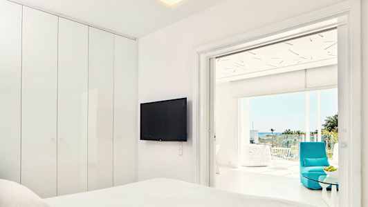 Moderne hotellrom med flatskjerm-TV og tilknyttet balkong med utsikt. (AI-generert tekst)