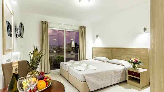 Bilde av et hotellrom med to enkeltsenger, et bord med frukt og drikke samt en balkong med utsikt. (AI-generert tekst)