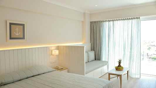 Et lyst soverom med en seng, en sofa og et bord med frukt. (AI-generert tekst)