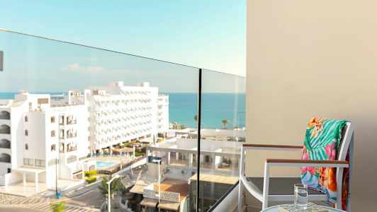 En balkong med utsikt over havet og omkringliggende bygninger. (AI-generert tekst)