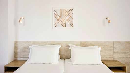 To enkeltsenger med hvitt sengetøy, en tretoppgavl, og en moderne veggdekor over. (AI-generert tekst)