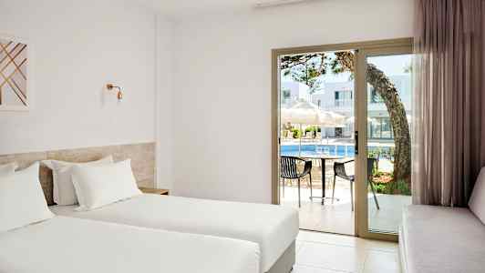 Hotellrom med to enkeltsenger, utsikt mot et basseng gjennom glassdører. (AI-generert tekst)