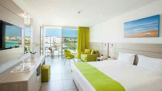 Moderne hotellrom med grønt interiør og utsikt over balkong og omgivelser. (AI-generert tekst)