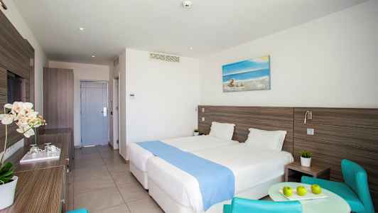 Hotellrom med to senger, et bord og stoler. (AI-generert tekst)