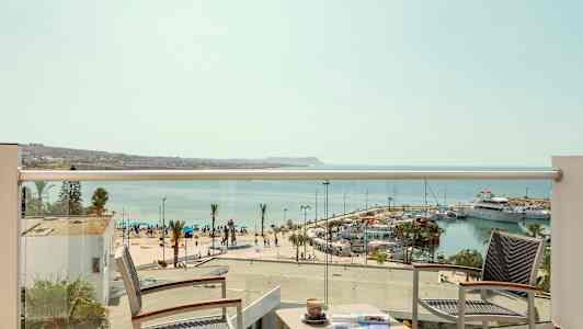 Utsikt fra en hotellbalkong over en marina og havet. (AI-generert tekst)