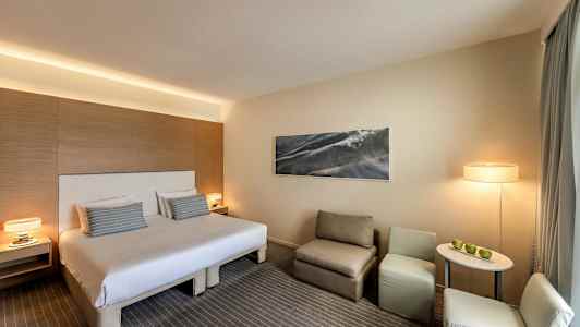 Hotellrom med dobbeltseng, sitteplass og bord. (AI-generert tekst)