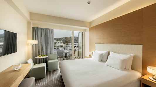 Hotellrom med dobbeltseng, sitteområde og balkong med utsikt. (AI-generert tekst)