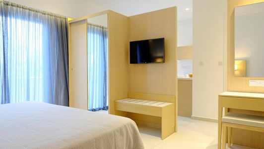 Hotellrom med seng, TV på veggen og speil ved et skrivebord. (AI-generert tekst)