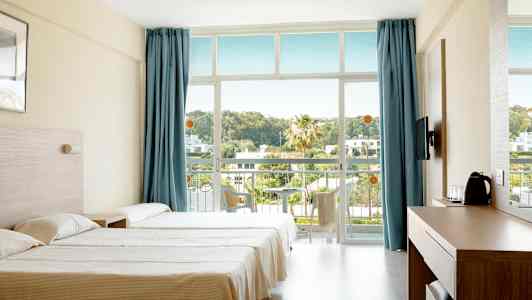 Et hotellrom med to senger, blå gardiner og en balkong med utsikt over grønne områder. (AI-generert tekst)