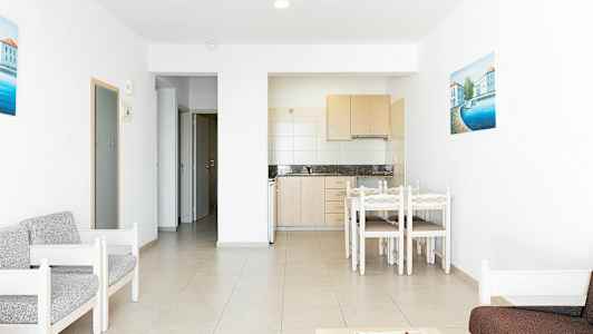 Et interiørbilde av et kjøkken og en stue med lyse møbler. (AI-generert tekst)