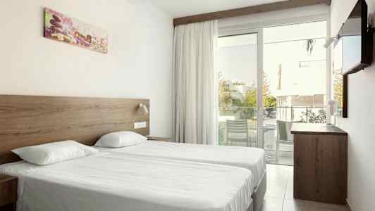 Dobbeltrom med to enkeltsenger, en glassdør til balkongen og en vegg-tv. (AI-generert tekst)