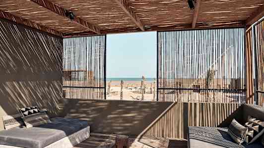 En åpen terrasse med sofaer der taket og veggene er av tre med havutsikt. (AI-generert tekst)