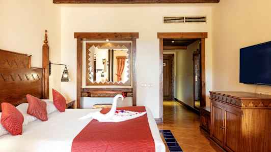 Et hotellrom med en dobbeltseng med røde puter og en dekorasjon formet som en svane på sengen. (AI-generert tekst)