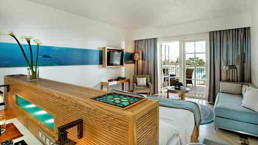 Innredning av et lyst hotellrom med sittegruppe og balkong. (AI-generert tekst)