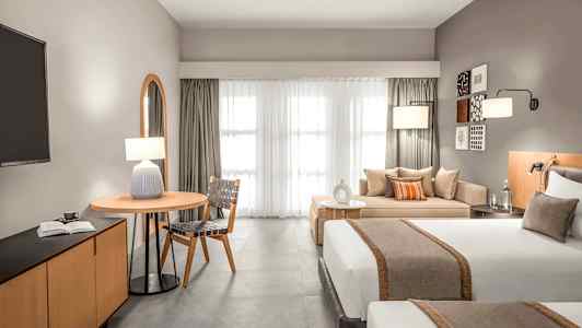 Moderne hotellrom med to senger, sittegruppe og et bord. (AI-generert tekst)