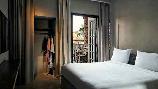 Hotellrom med seng, balkong og garderobe. (AI-generert tekst)