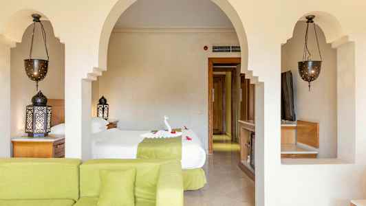 Stue med grønn sofa, soverom med to enkeltsenger, orientalske lamper og belyste detaljer. (AI-generert tekst)