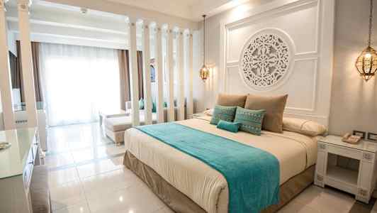 Et elegant hotellrom innredet med en stor seng, dekorative detaljer og myke farger. (AI-generert tekst)