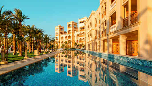 En bygning med arkitektoniske detaljer og et basseng i forgrunnen. (AI-generert tekst)