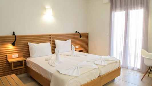 To senger med hvitt sengetøy, en tre-hodegjerde og dekorative håndklær formet som svaner. (AI-generert tekst)