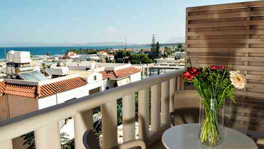Utsikt fra balkong med møbler, blomster på bordet og havet i bakgrunnen. (AI-generert tekst)