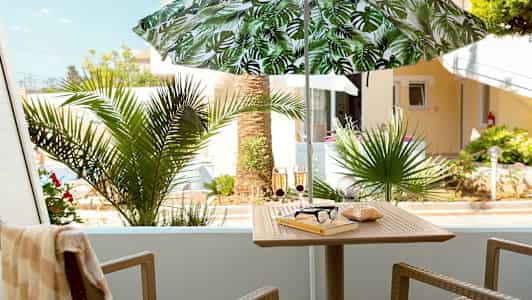 Balkong med parasoll, bord, stoler og utendørs beplantning. (AI-generert tekst)