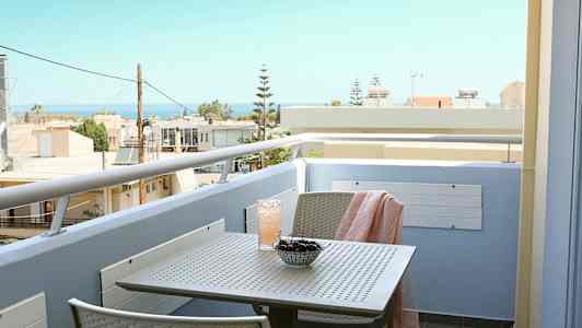 En balkong med utsikt mot havet, med et bord med kirsebær og en drikke. (AI-generert tekst)