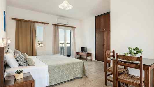 Et soverom med en dobbeltseng, et lite bord med to stoler og et skap. (AI-generert tekst)