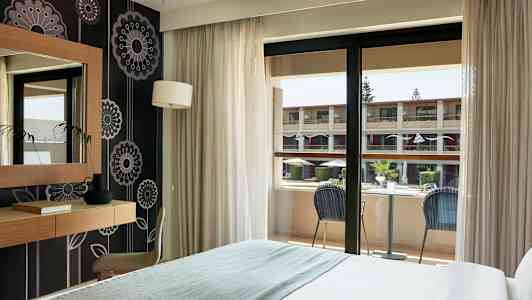 Et hotellrom med balkong som vender mot en indre gårdsplass. (AI-generert tekst)